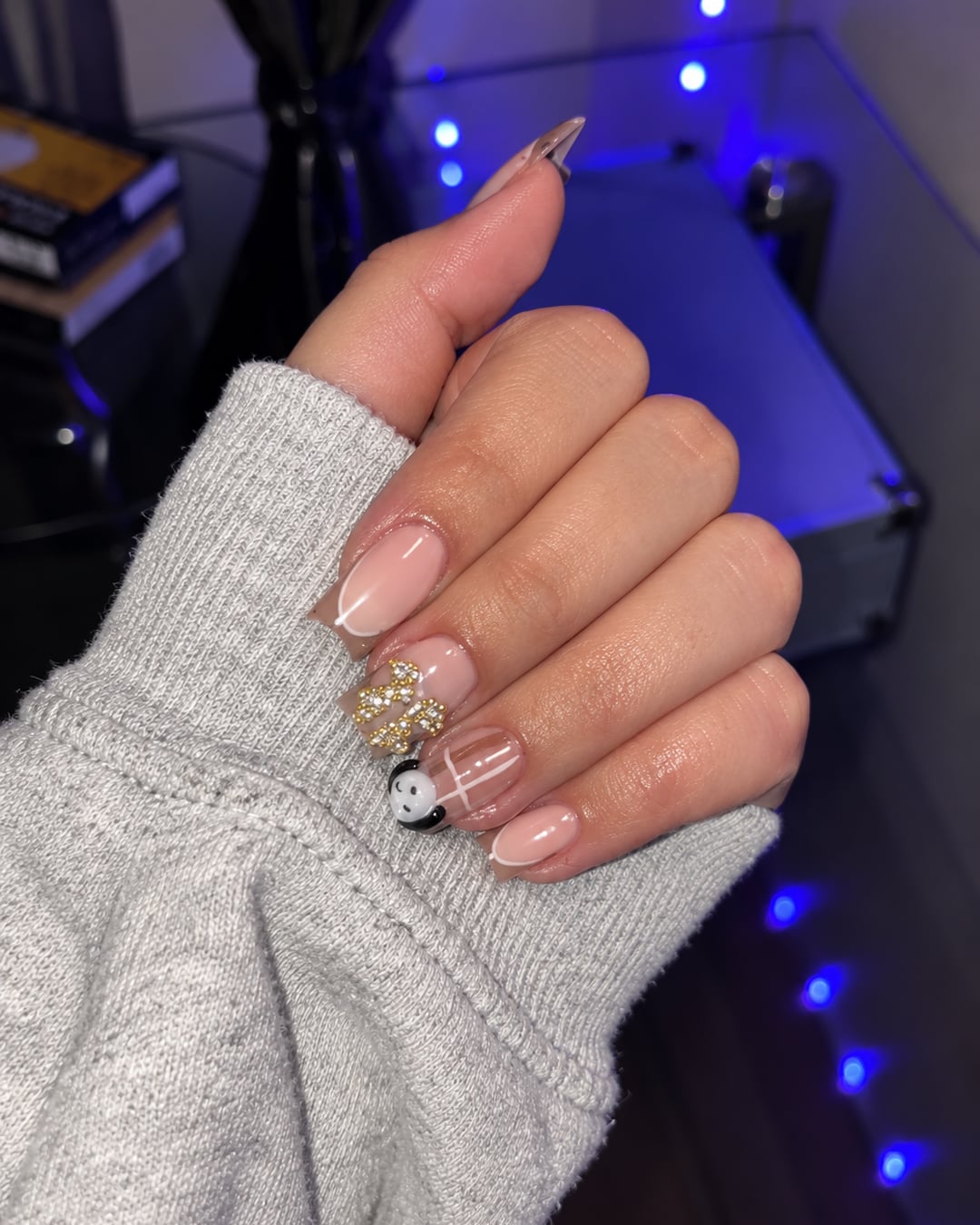 Ongles amande nus avec liserés blancs, strass dorés et charm panda
